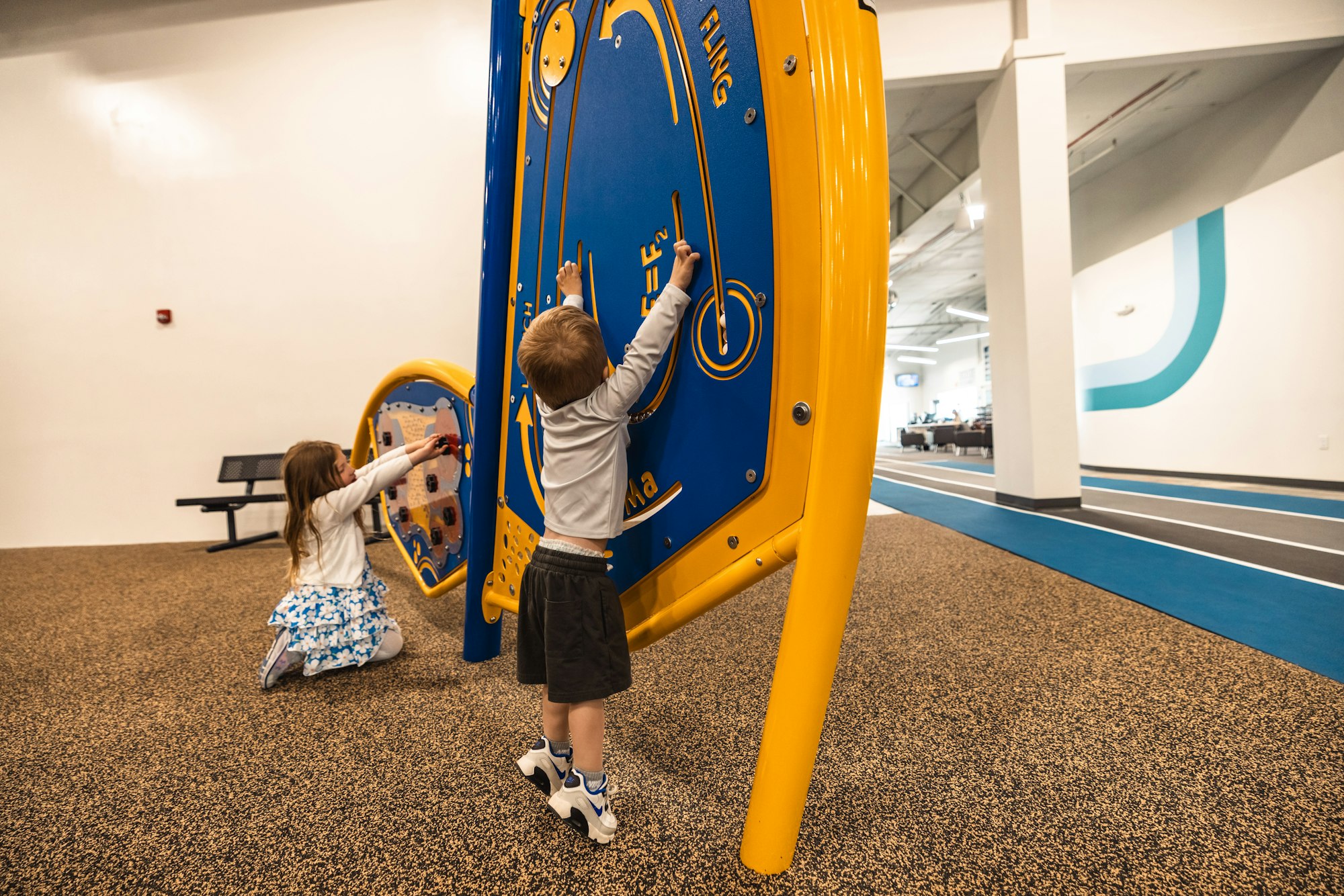Two children playing with an interactive wall game in an indoor play area.