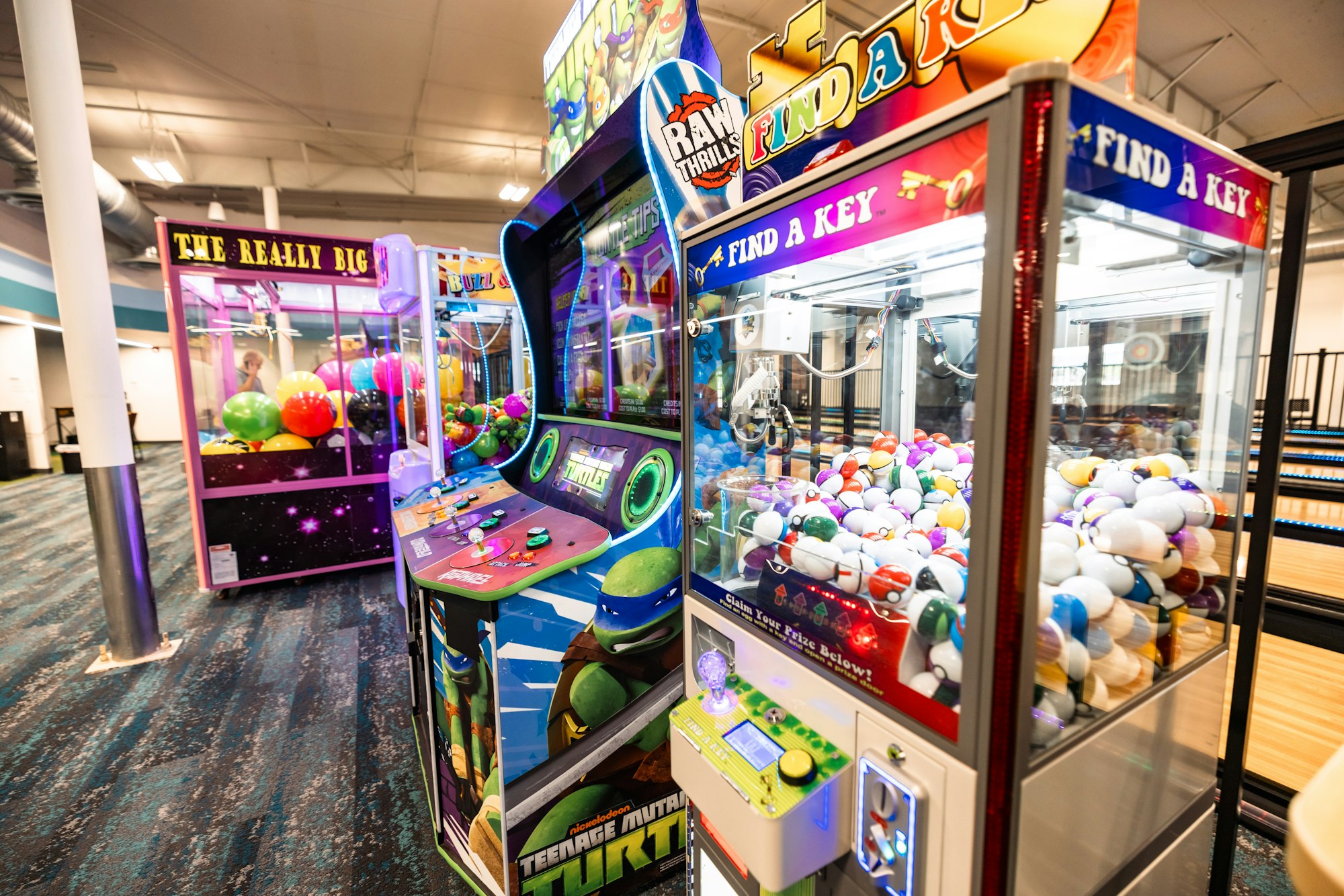 Arcade games and claw machines with prizes inside.