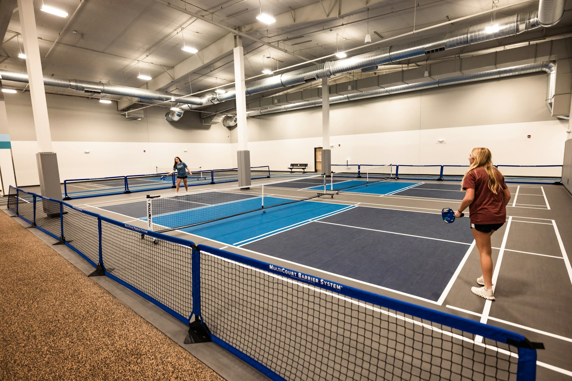 Indoor pickleball courts with people playing.