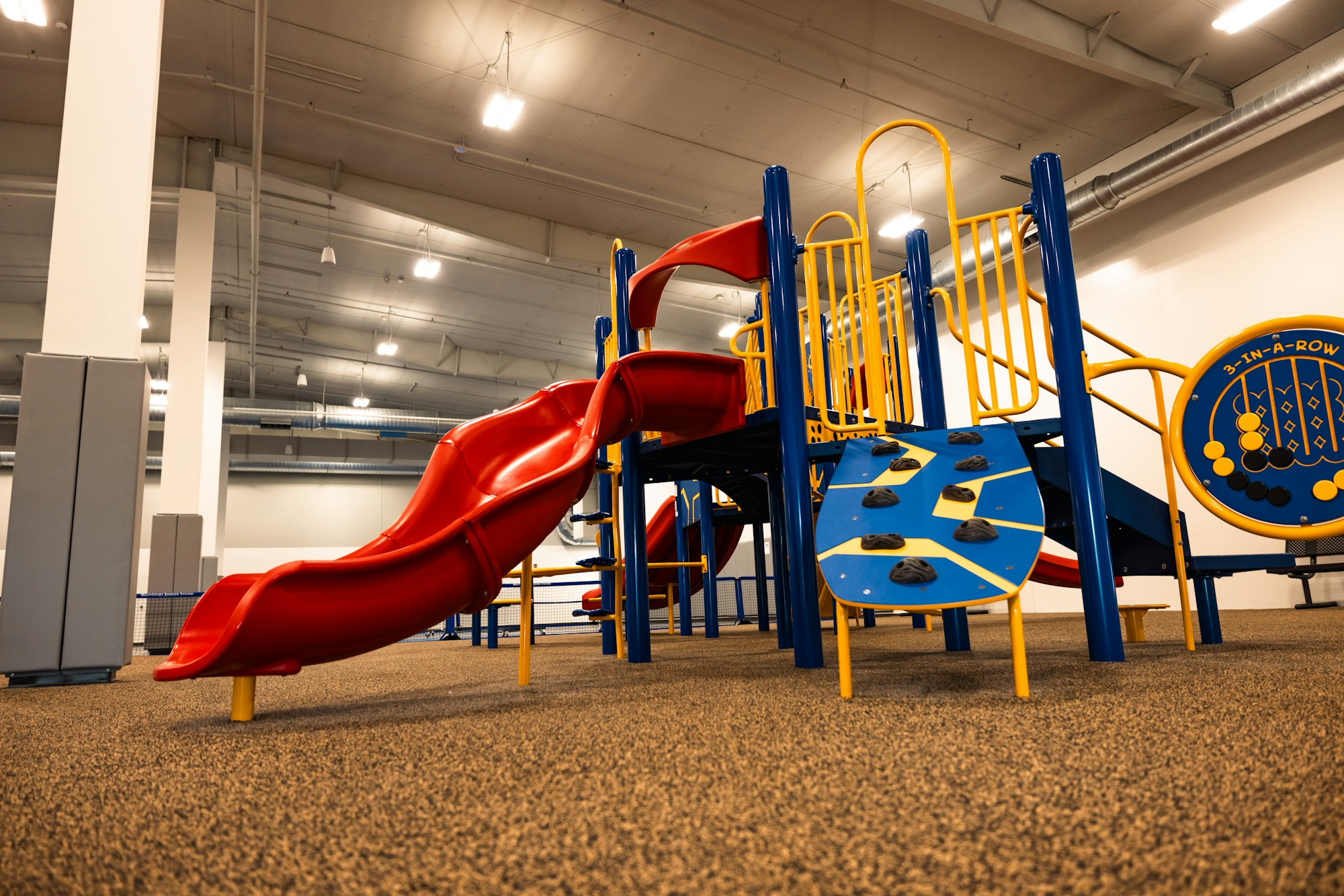 Indoor children's playground with a slide, climbing structures, and games.