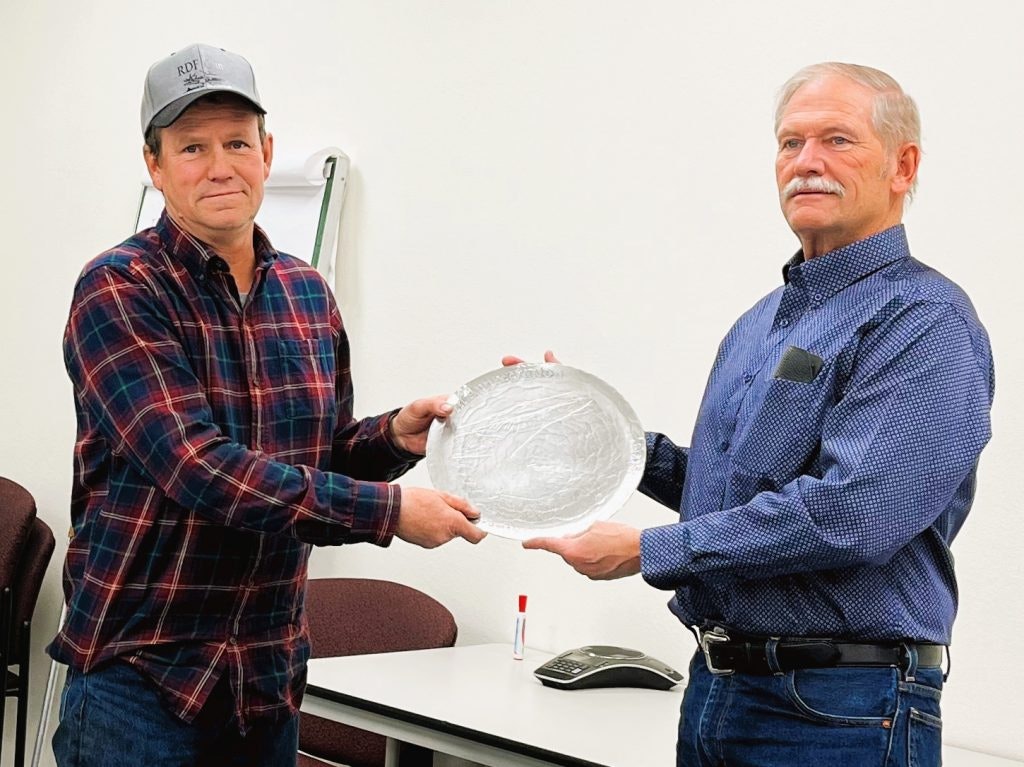 Photo of two men, one handing the other an award