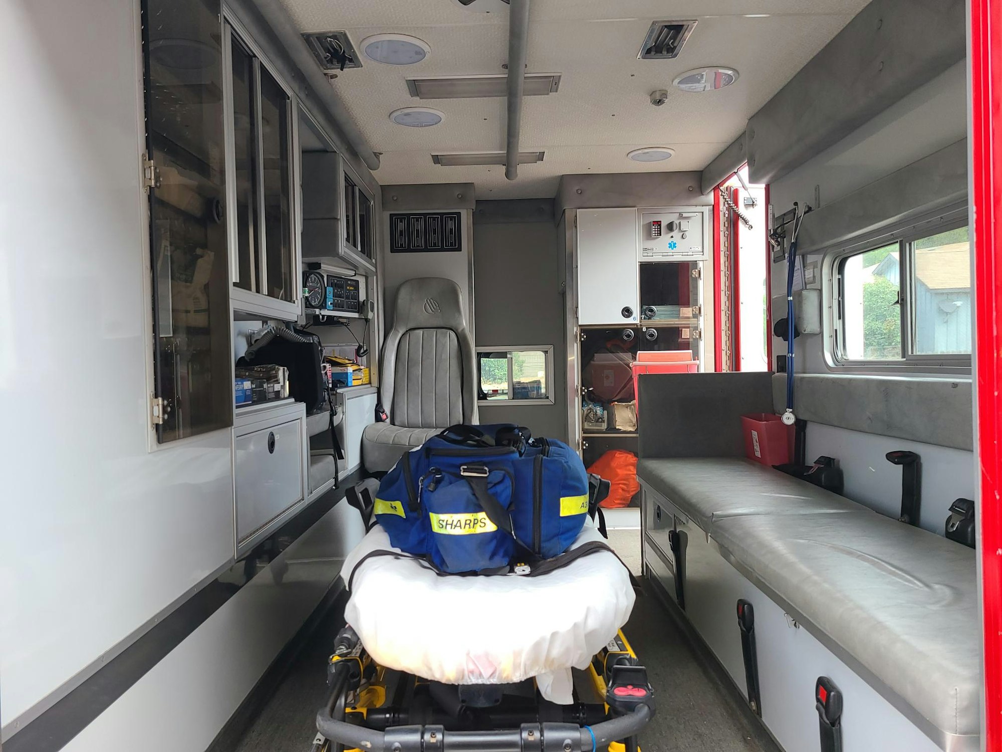 Interior of an ambulance with medical equipment, a stretcher, and a bench seat.