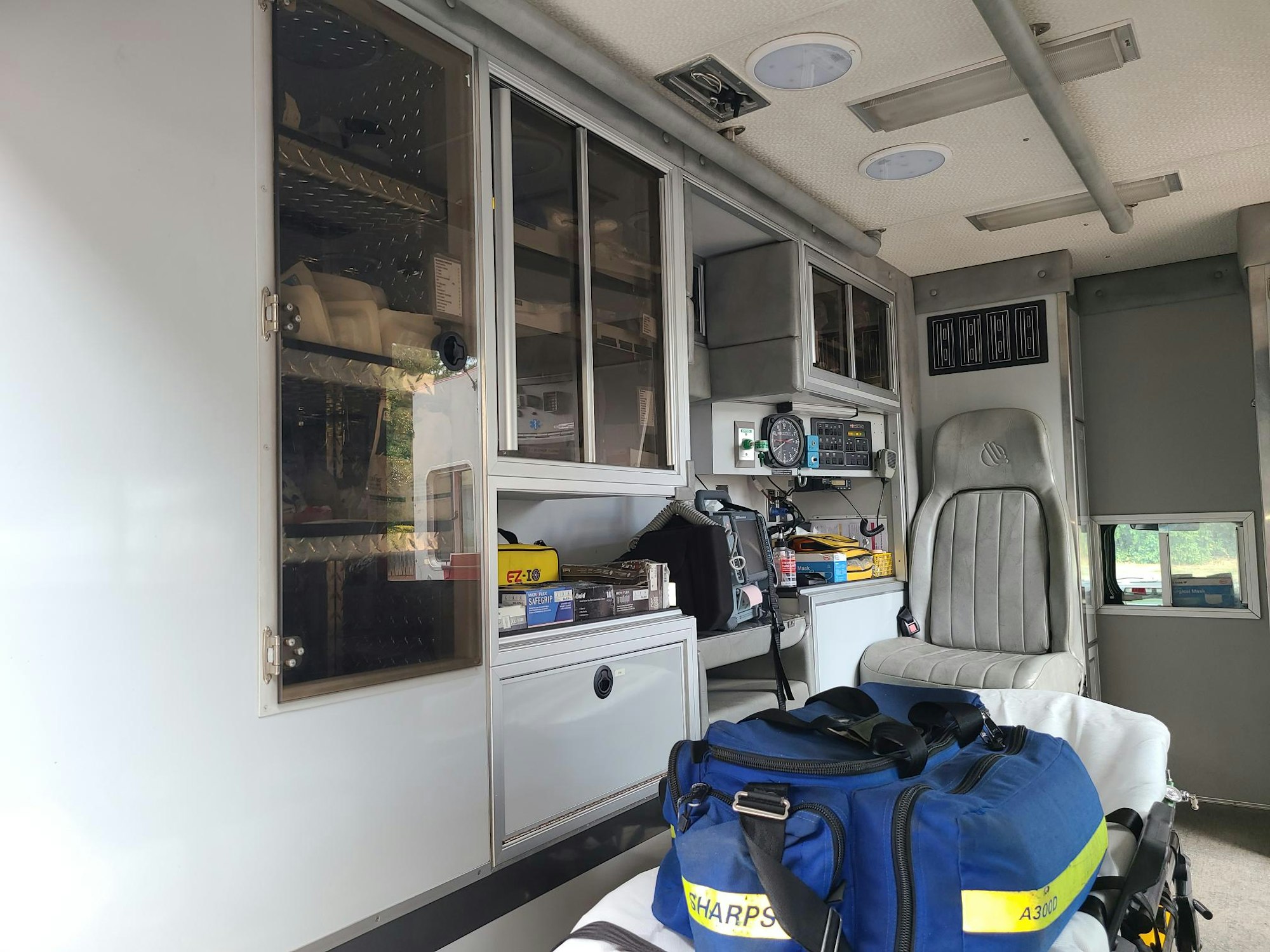 Interior of an ambulance showing medical equipment, a seat, and storage compartments.