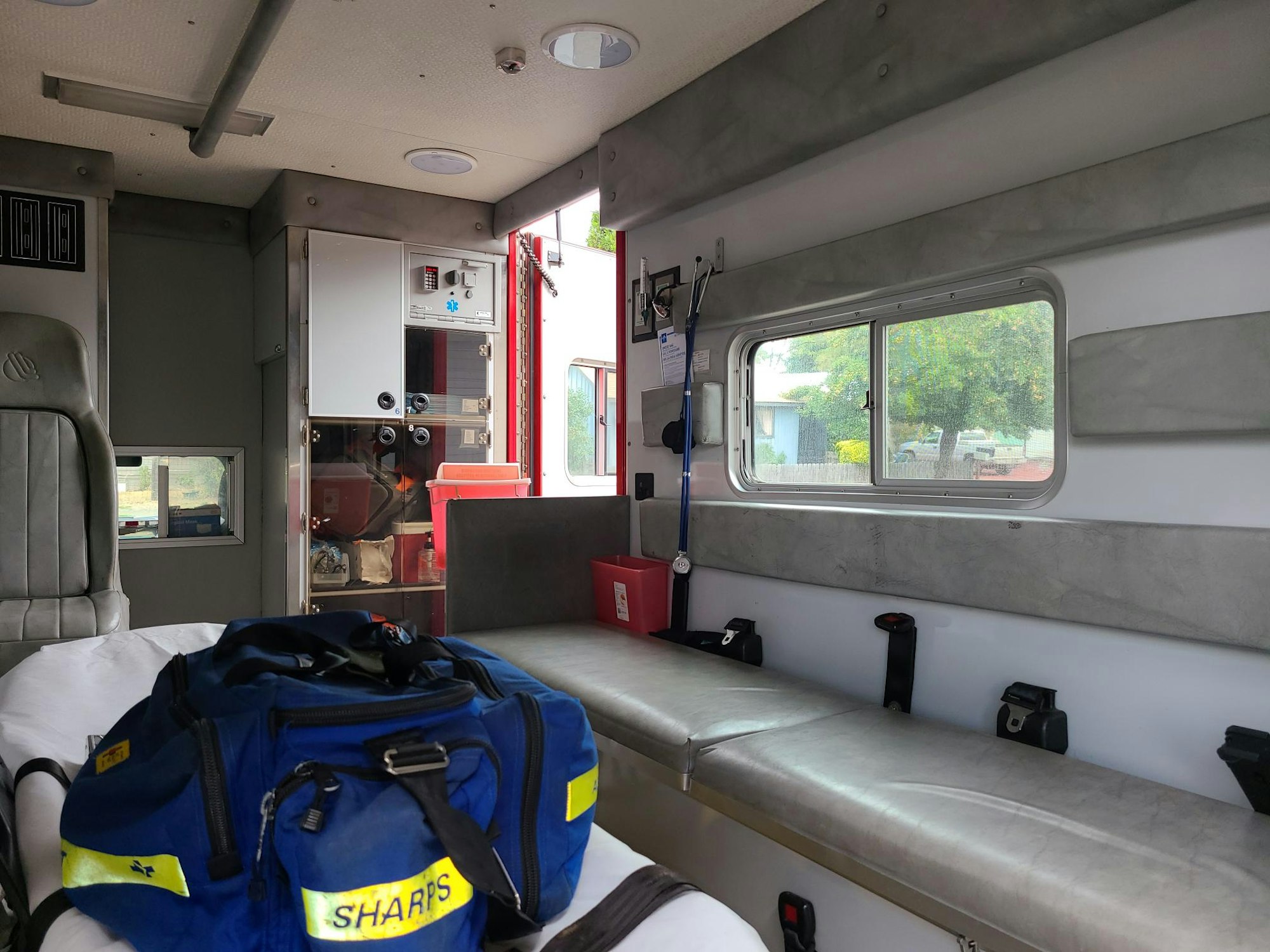 Interior of an ambulance with medical equipment and a bench seat.