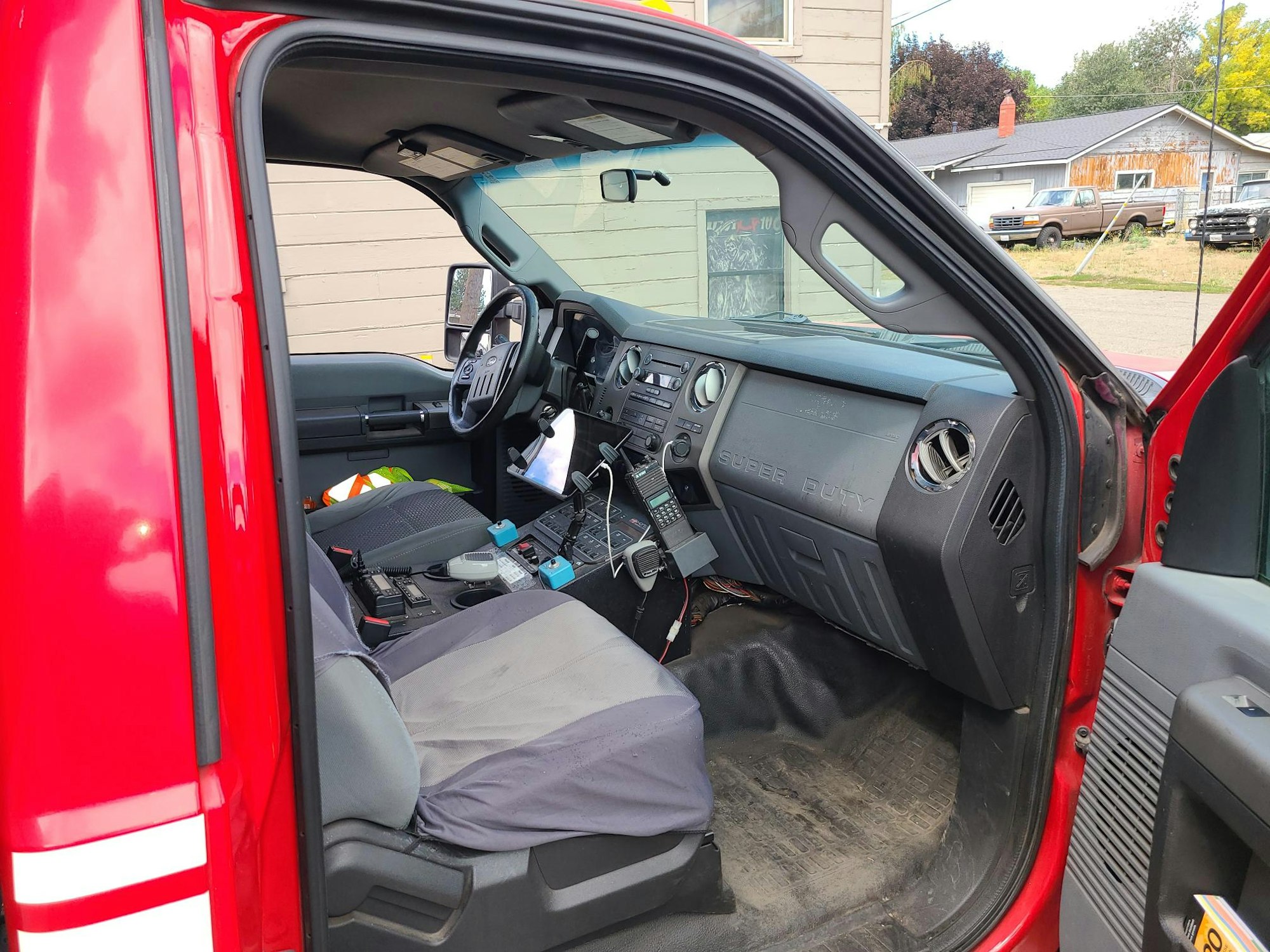 A cluttered red truck's interior with various items on the seats and dashboard.