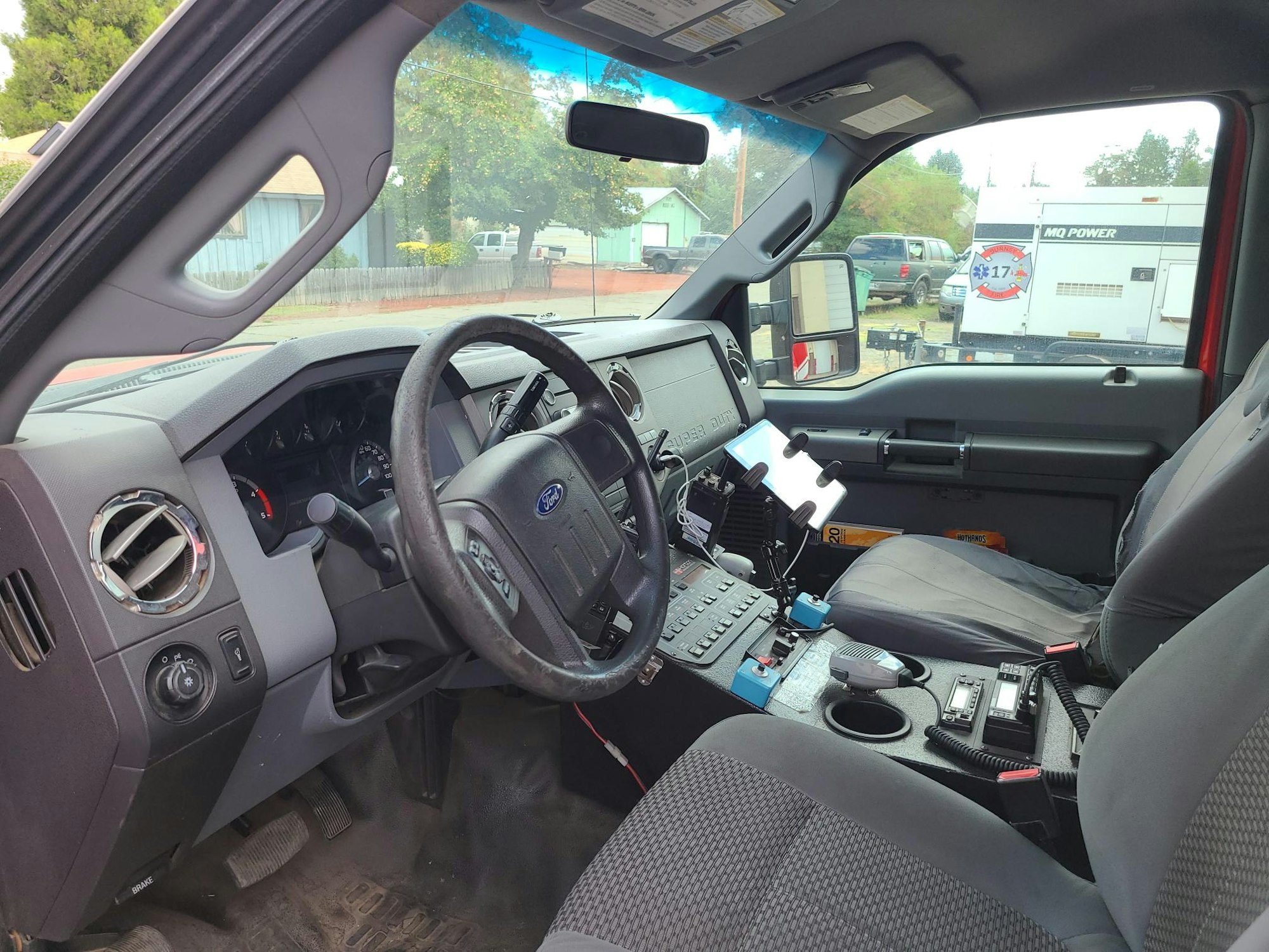 Interior of a police vehicle with radio equipment, computer mount, and steering wheel.