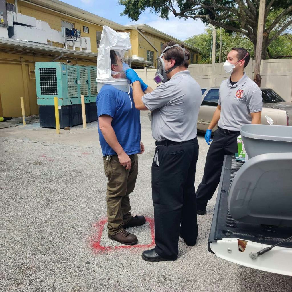 Picture of 3 people, one person being "Fit" tested for PPE