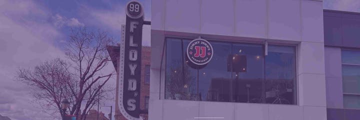 Building with "FLOYD'S" sign and "Jimmy John's Sandwiches" logo on the window; tree and partly cloudy sky visible.
