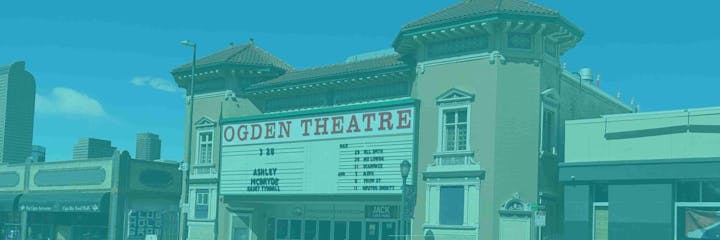 A theater with a marquee displaying upcoming events, set against a cityscape background.