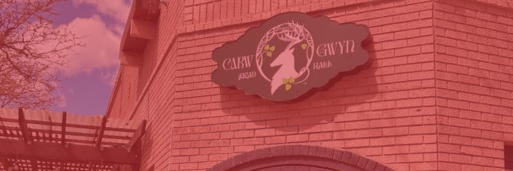 The image shows a sign for "Cairn Mead Hall," with a decorative design featuring a stylized deer and some leaves.