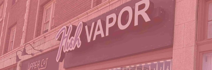 Shop signs reading "Hush VAPOR" and "UPPER CUT" on a building.