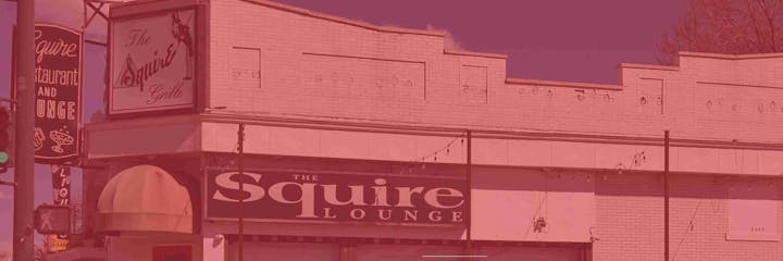 A building labeled "The Squire Lounge" with signs for the Squire Restaurant and Grille, featuring bright neon-style signage.