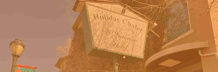 A Victorian-style hotel sign reads "Holiday Chalet" with a stained-glass window and a streetlamp nearby.