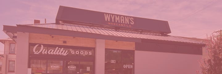 The image shows a storefront labeled "Wyman's Mercantile," highlighting the phrase "Quality Goods" and an "Open" sign.