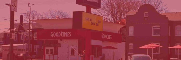 A restaurant named "Goodtimes" with a sign advertising late-night hours, street signs, and umbrellas outside.