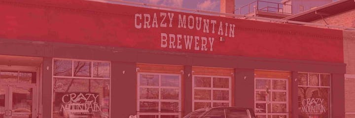 Crazy Mountain Brewery building facade, with red signage and glass windows.
