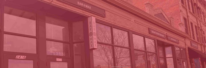 Storefront with signs for "Bar Max," "Bryant of New York Hair," and "Beyond Nails." Red-tinted brick facade visible.