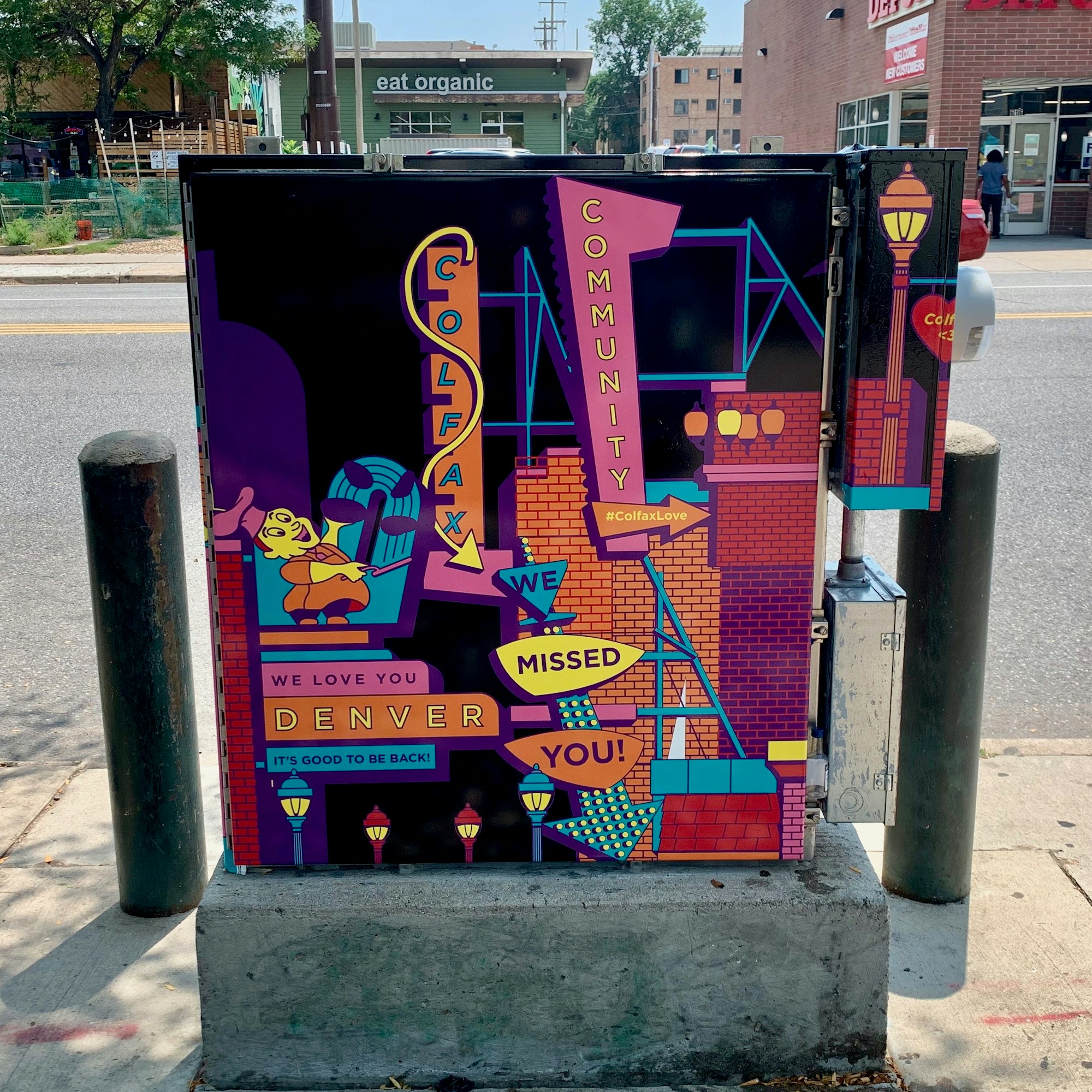 Colorful street art on a utility box with messages: "COLFAX COMMUNITY," "We love you DENVER," "We missed you!" #ColfaxLove