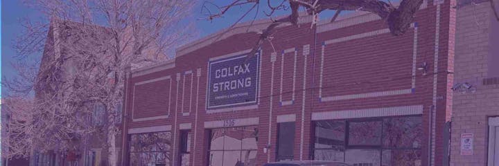 Brick building with a sign reading "COLFAX STRONG Strength & Conditioning," barren trees, and a car parked in front.