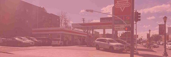 Gas station with several cars, a "Conoco" sign, and fuel prices displayed.