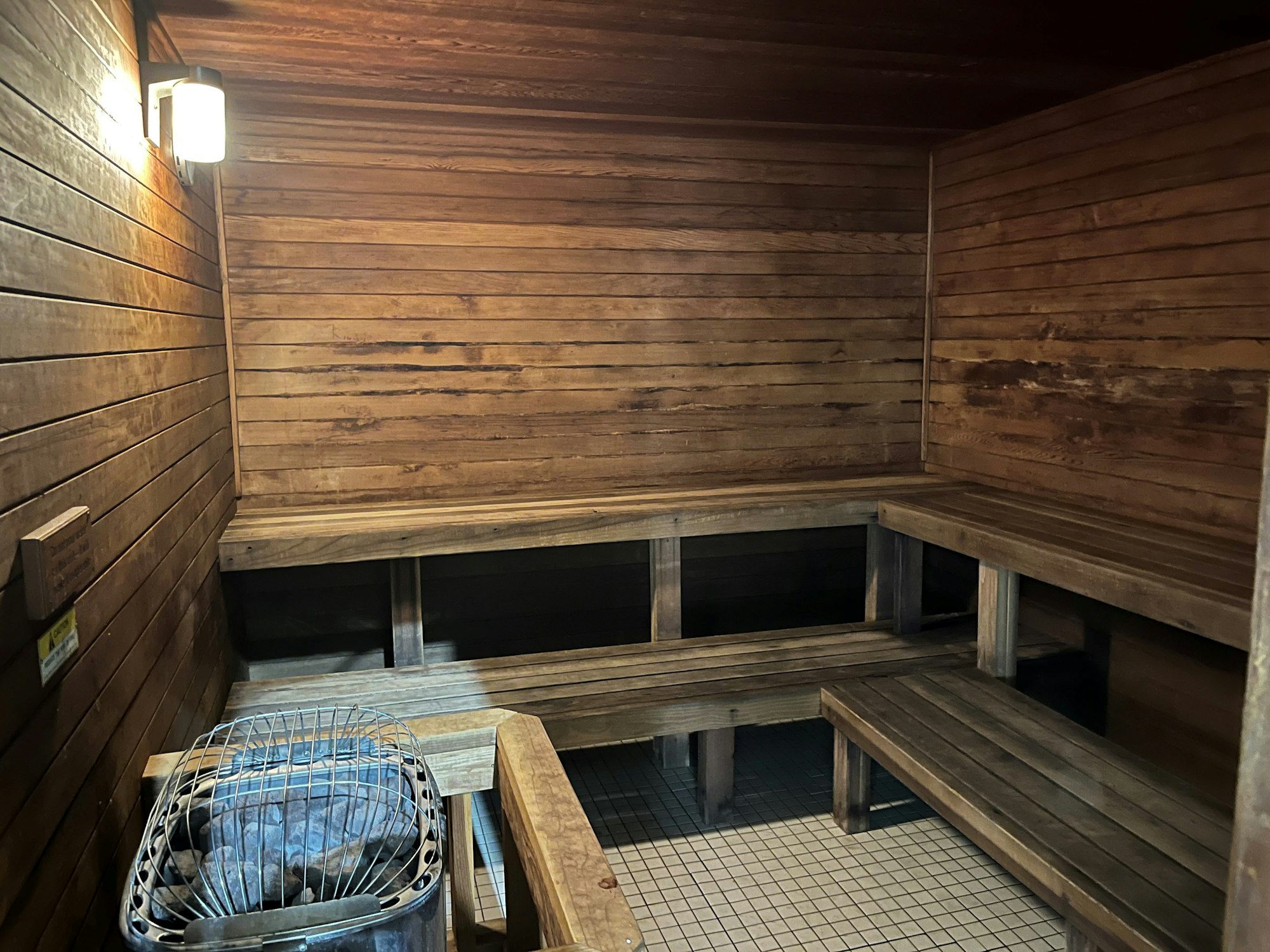The image shows a wooden sauna interior with benches and a heater, creating a warm, relaxing atmosphere.