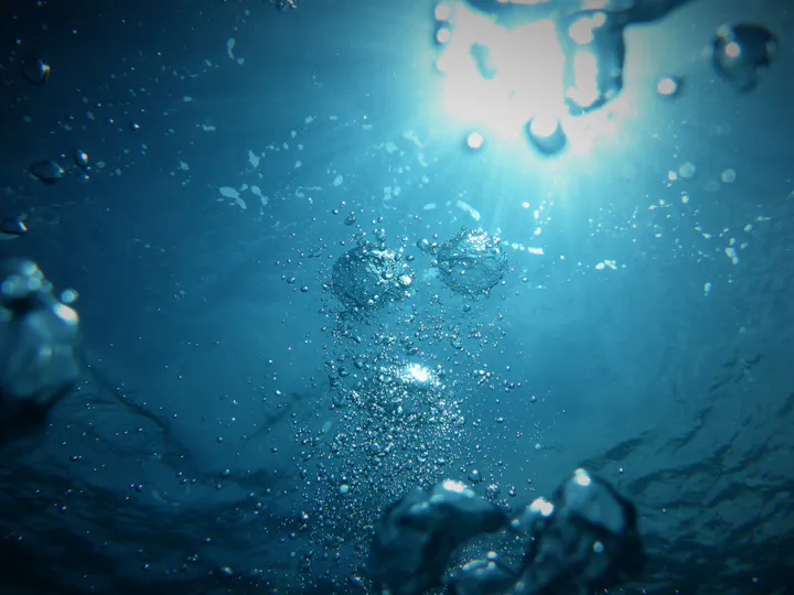 An underwater scene with sunlight filtering through water, featuring bubbles and a serene blue background.