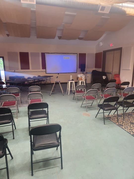 May contain: people, person, indoors, architecture, building, classroom, room, school, electronics, screen, chair, furniture, crowd, home decor, rug, speaker, and projection screen