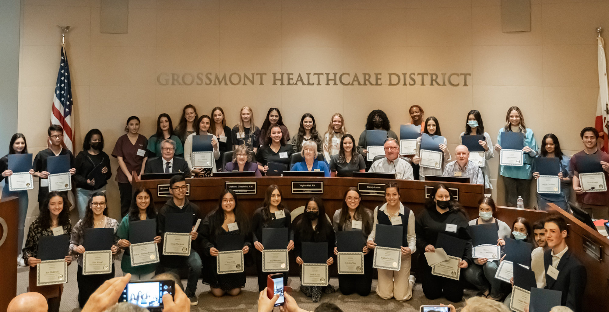 A group celebrating with certificates at the Grossmont Healthcare District, acknowledging their achievements.