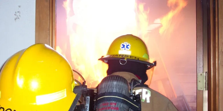 A firefighter facing intense flames during an active fire situation.