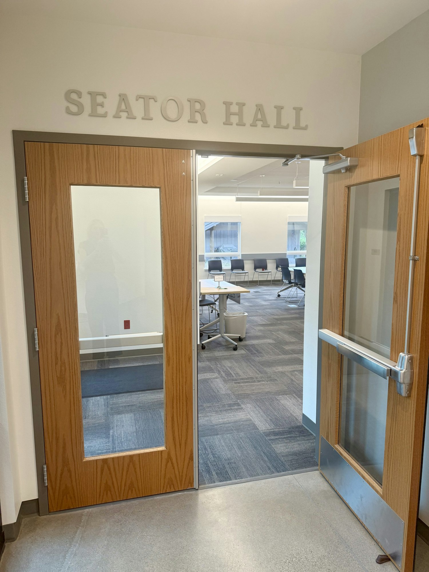 Open door to Seator Hall with view into a modern room with chairs and tables.