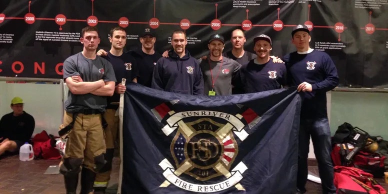 A group of firefighters holding a banner of their fire station.