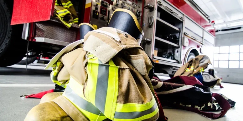 Firefighter gear in front of a fire truck inside a station.