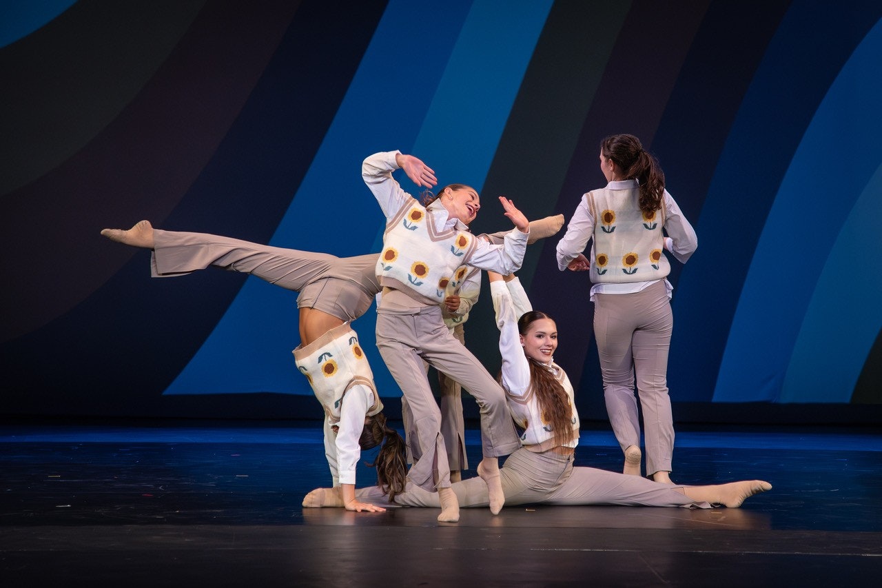 A dance performance featuring four dancers in coordinated outfits with floral designs, showcasing dynamic poses on stage.
