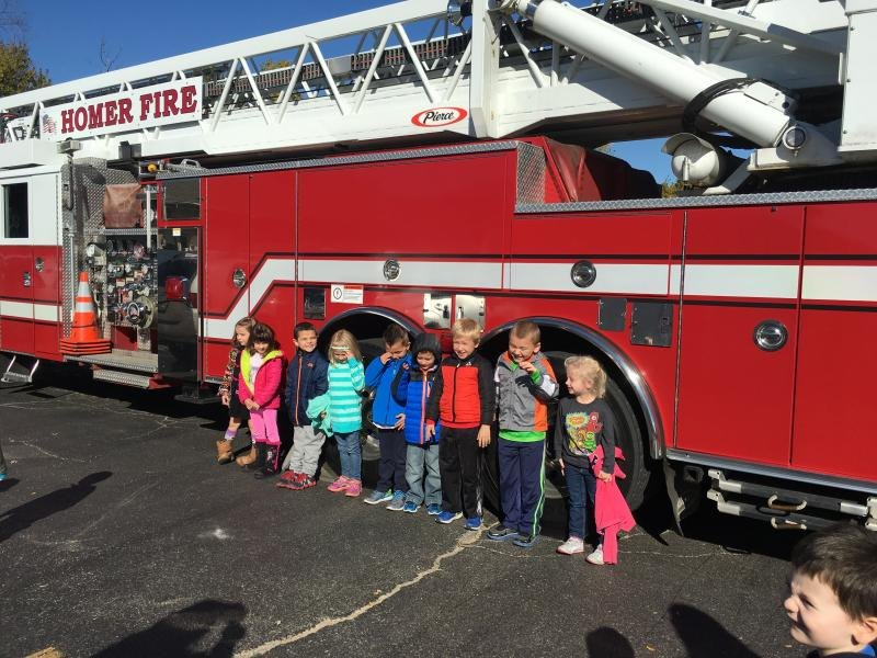 Children posing in front of a red fire truck marked "Homer Fire."