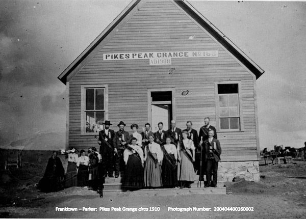 A group of people standing in front of the Pikes Peak Grange building, circa 1910.