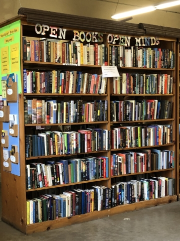 A bookshelf with "OPEN BOOKS OPEN MIND" sign, filled with various books.