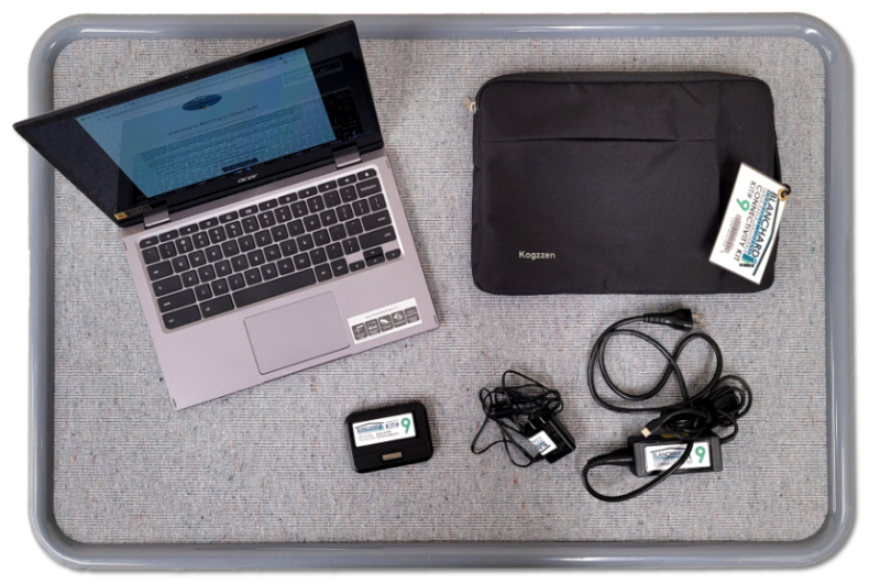 Laptop, chargers, laptop sleeve, and portable hard drive on a tray.