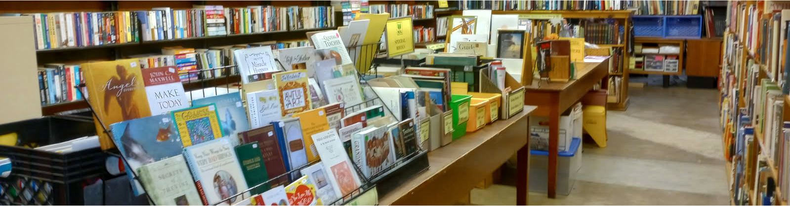 Books displayed on tables and shelves in a cozy bookstore or library setting.