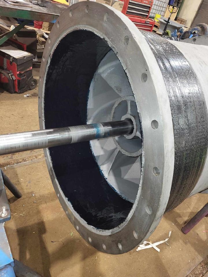 The image shows a section of industrial machinery, likely part of a turbine or motor, featuring a cylindrical casing and a central shaft.
