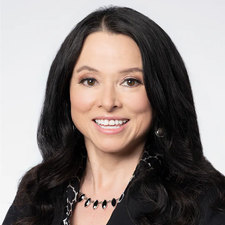 The image features a woman with long black hair, smiling, wearing a black and white outfit, and a necklace. Background is light.