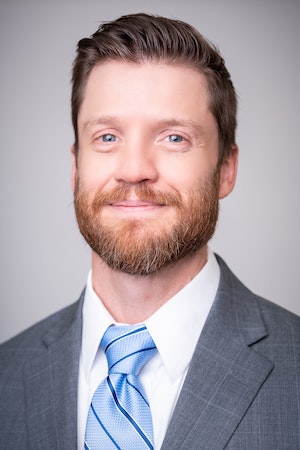 A smiling man with a beard wearing a suit and tie.