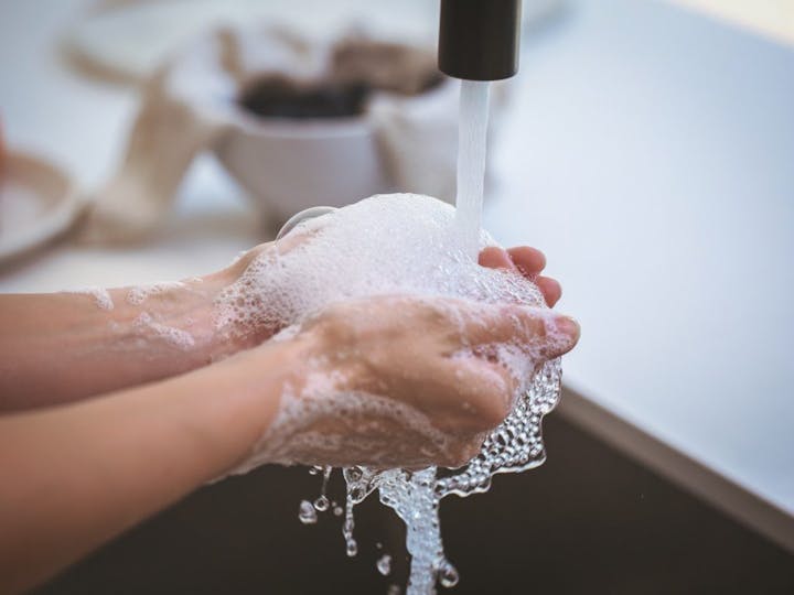 A person washing hands with soap under running water.