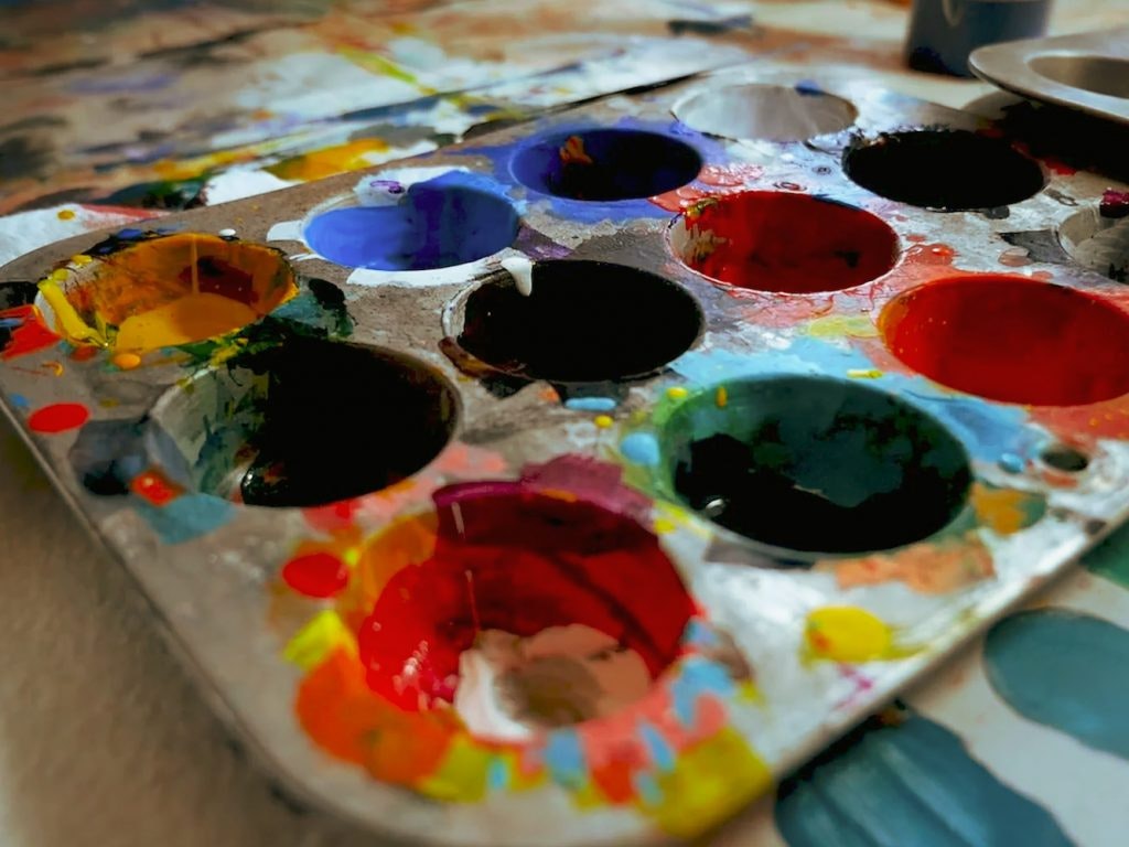 A well-used, colorful paint palette with multiple hues.