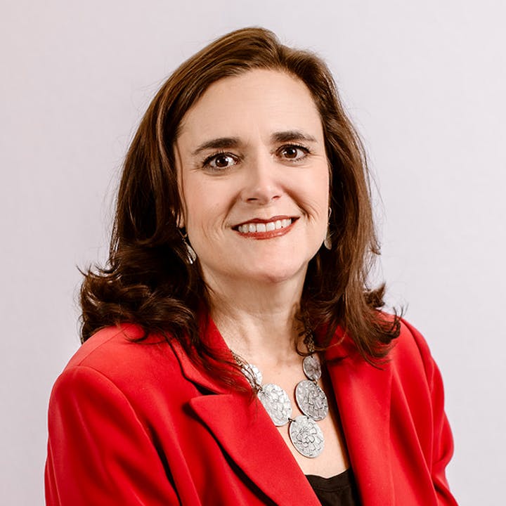 A woman in a red blazer smiles at the camera