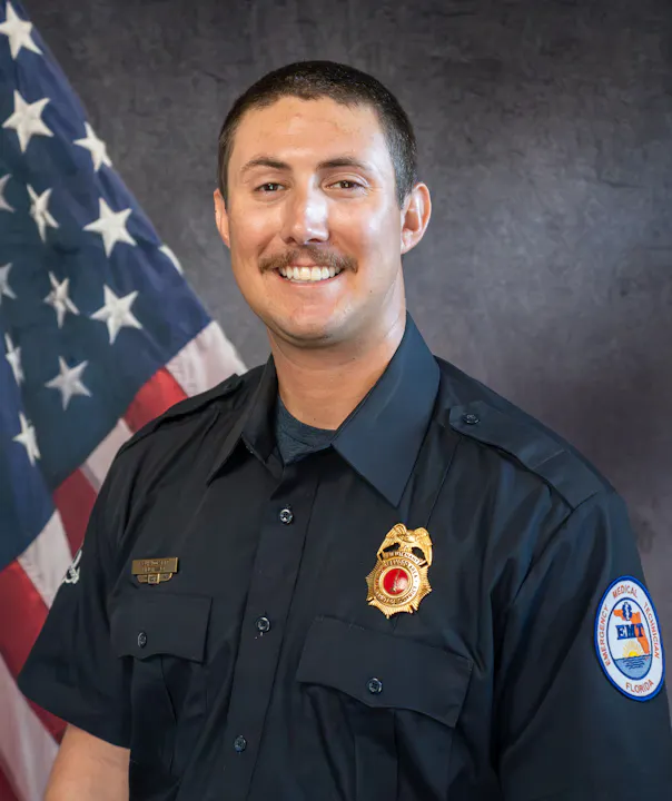 The image features a smiling uniformed individual with a badge, posing in front of an American flag backdrop.