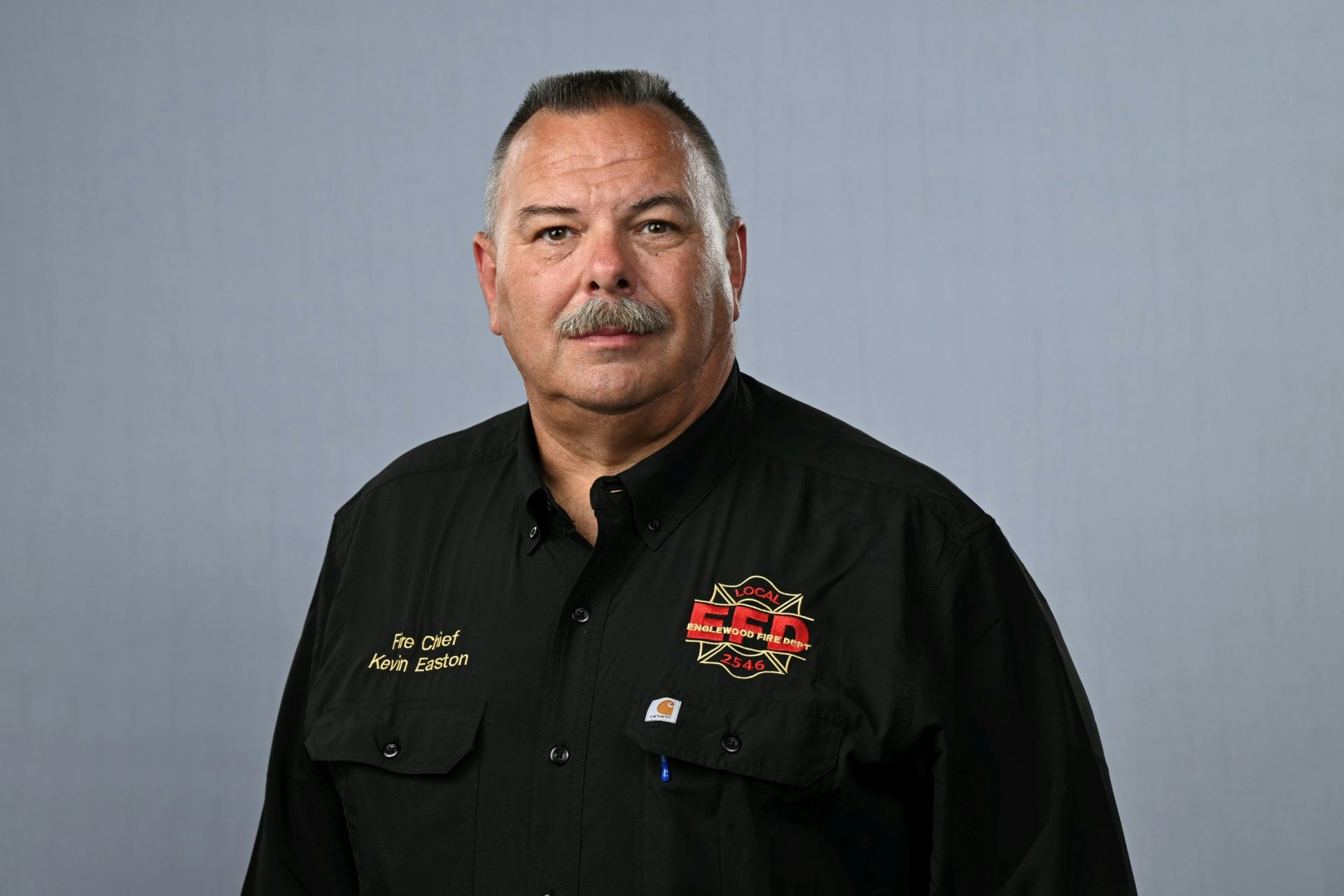 A man with a mustache in a uniform labeled "Fire Chief Kevin Easton" with Englewood Fire Dept. patches.