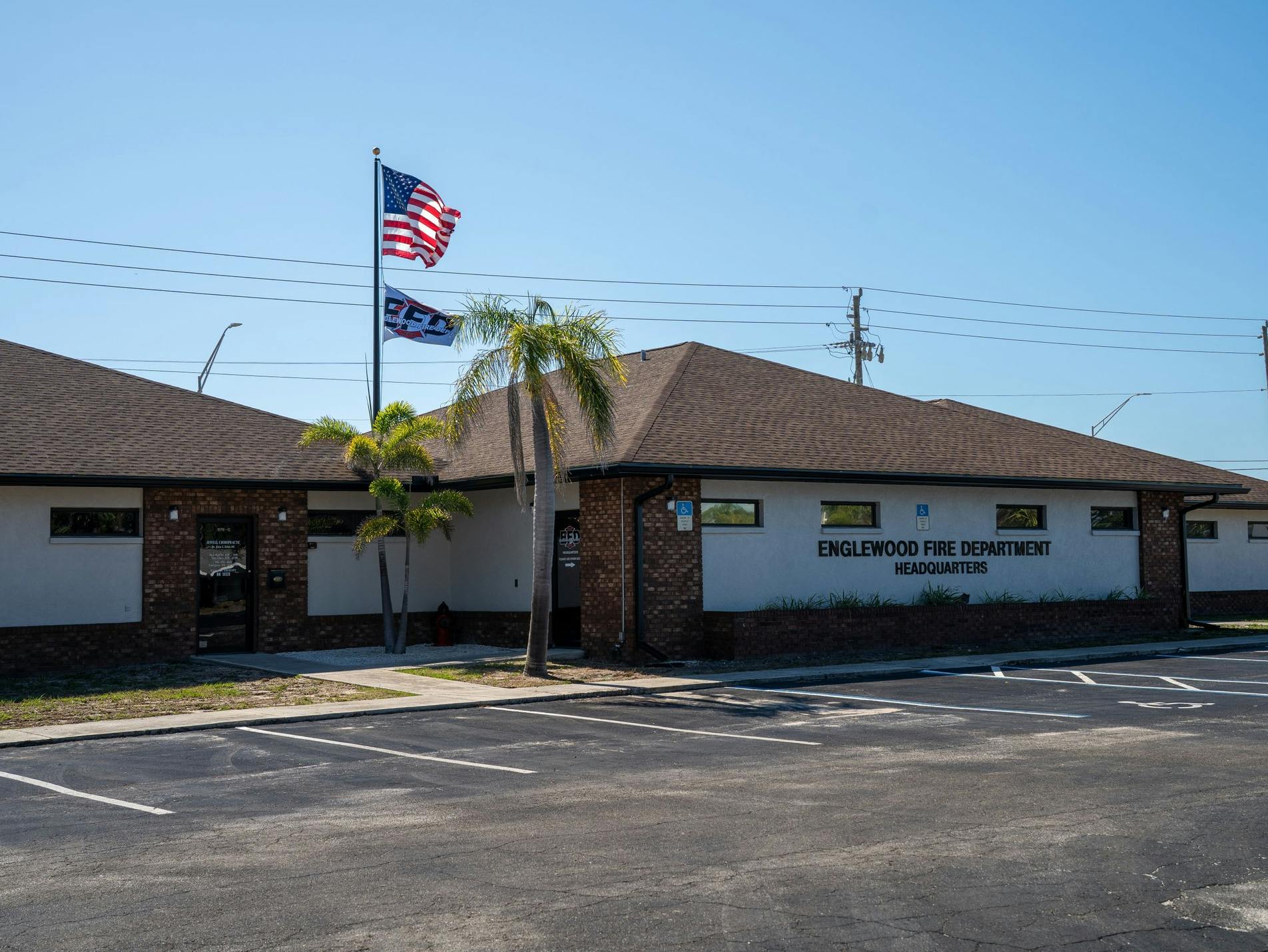Building labeled "Englewood Fire Department Headquarters" with flags outside, set in a parking lot.