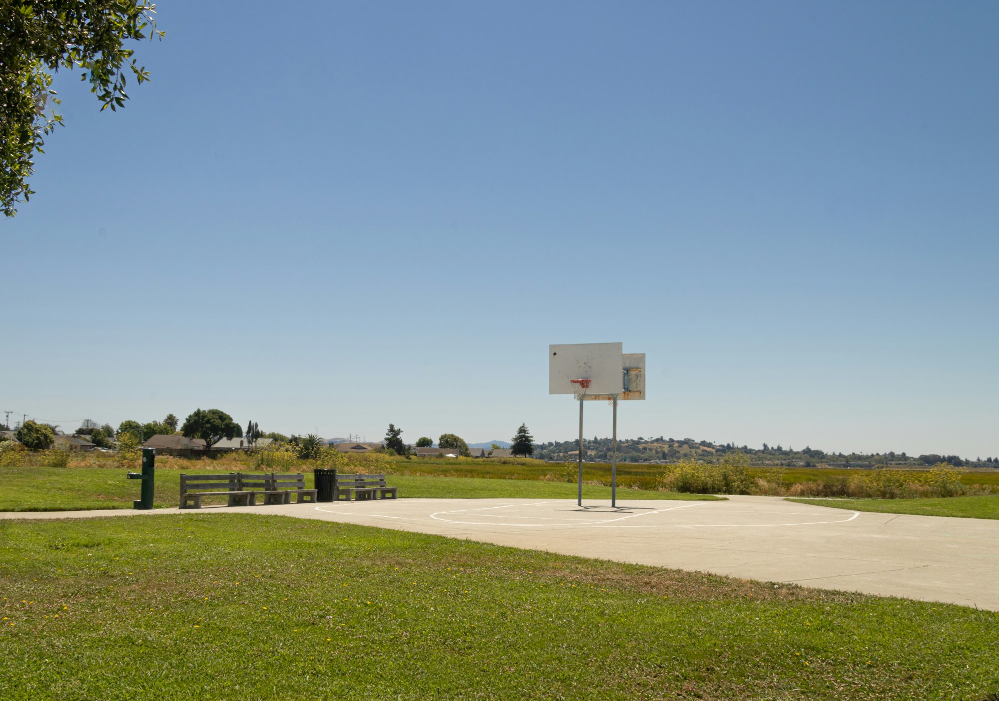 Outdoor basketball court with clear blue sky.