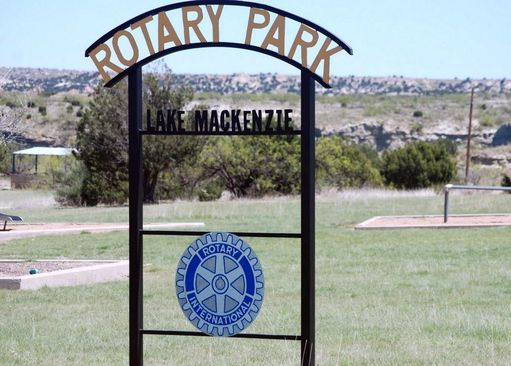 Sign for Rotary Park at Lake Mackenzie, featuring the Rotary International logo. The park is set in an open, grassy area.