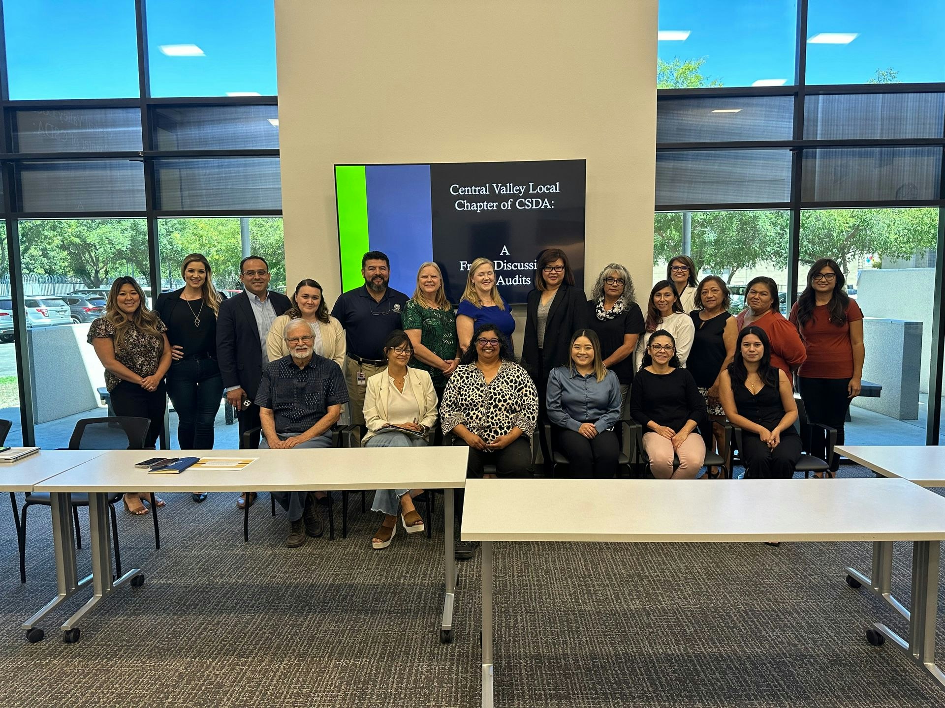 A group of people posing indoors in front of a sign for the Central Valley Local Chapter of CSDA.